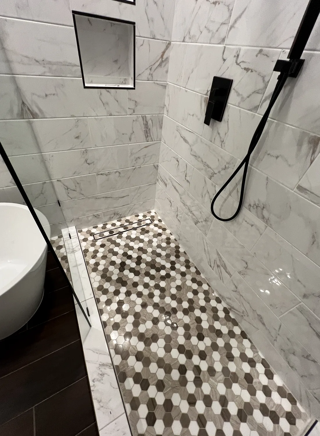 Marble look shower tile installation in Charlotte NC with niche and mosaic floor